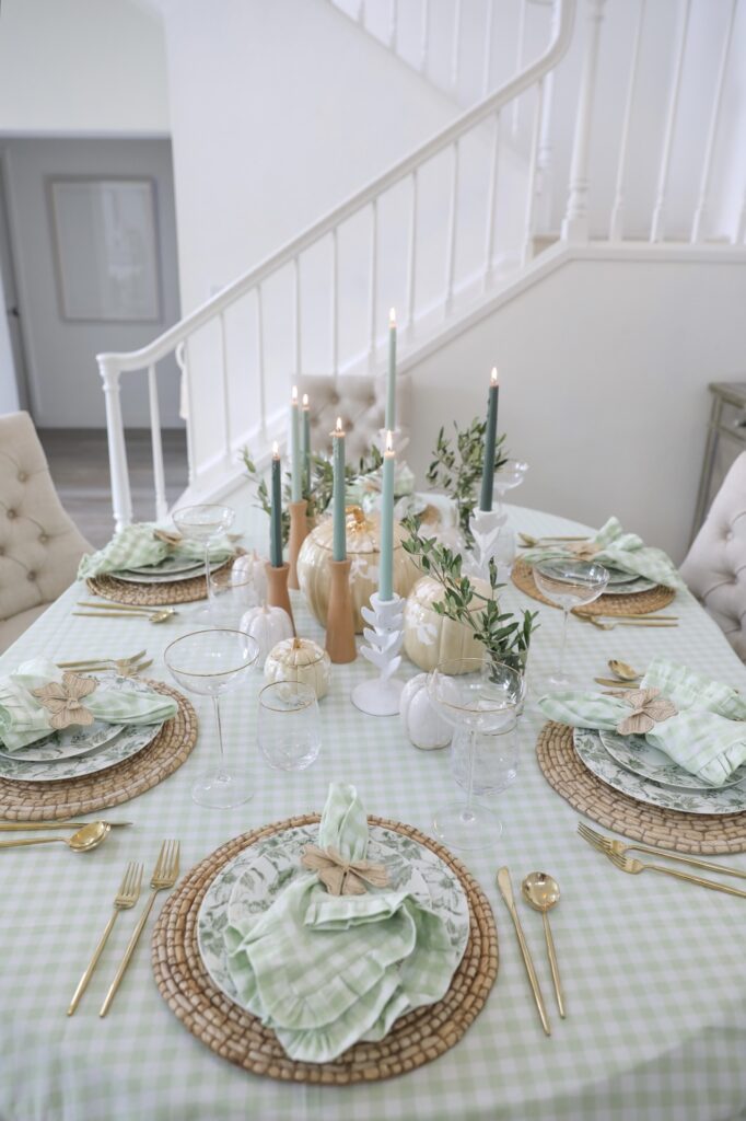 Fall greens tablescape with gold accent ceramic pumpkins and light reen gingham tablecloth and napkins, with ombre candle sticks.