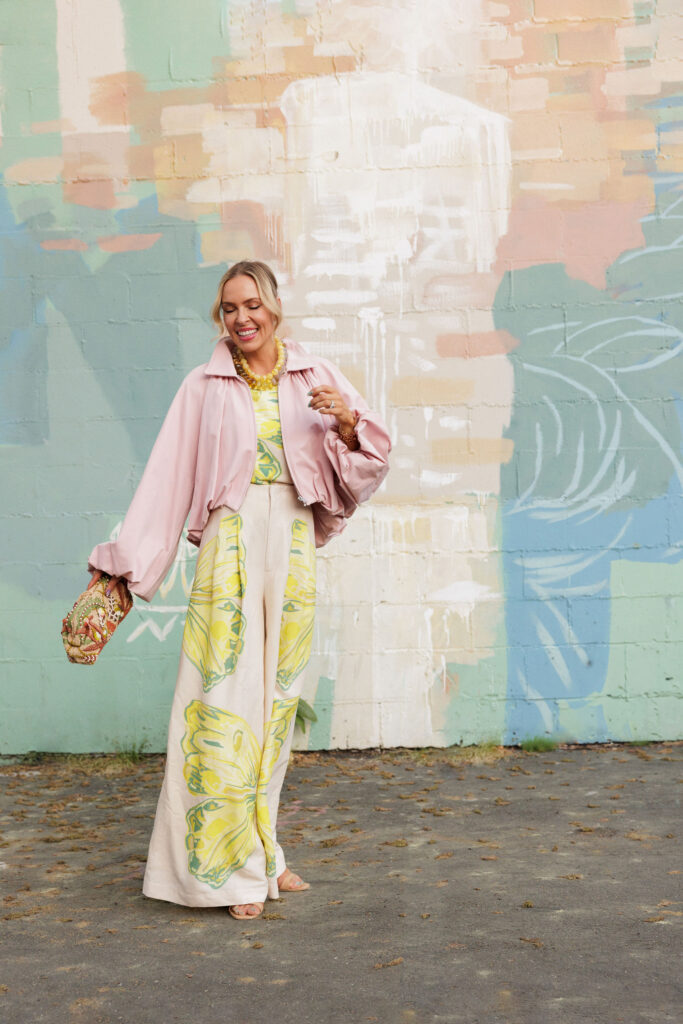 pastel spring outfit with pink cropped jacket yellow printed dress and statement necklace