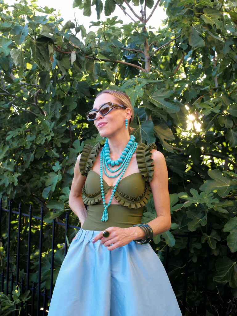 Colorful spring summer fashion outfit featuring turquoise jewelry, olive swimwear, and bold resort-style accessories.