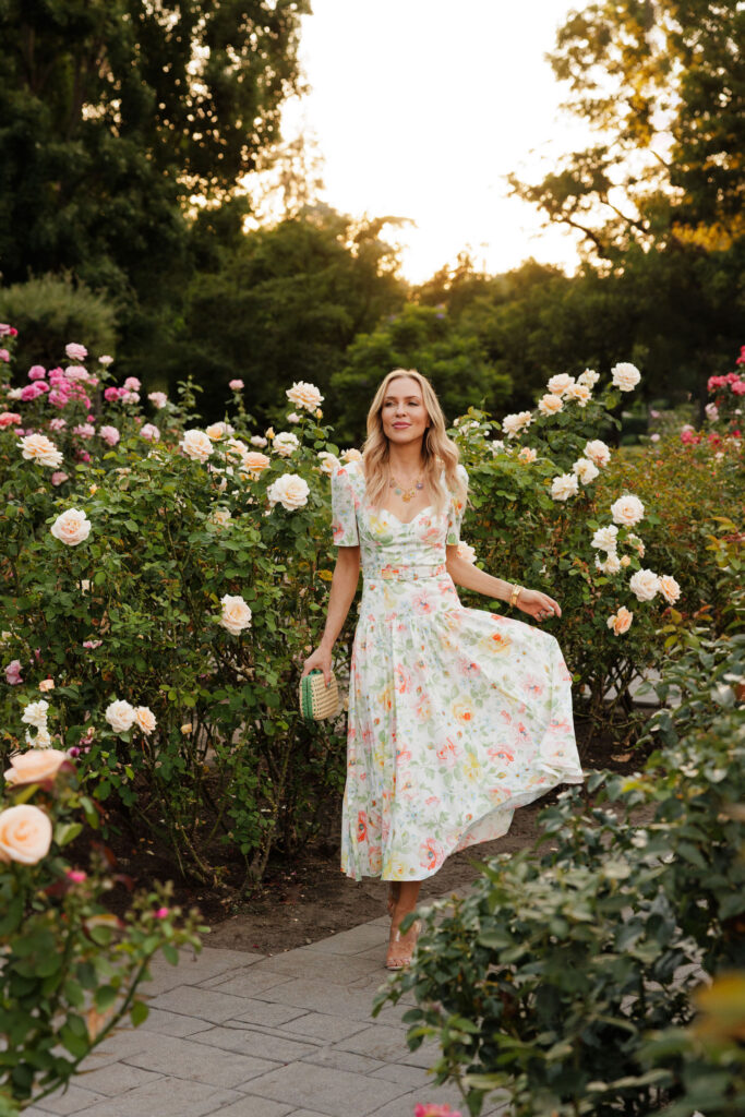 Floral Needle & Thread dress photographed among blooming cream roses at sunset